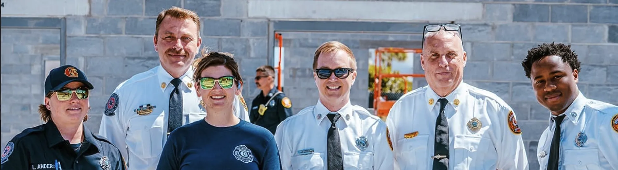 Firefighters in uniform smiling together outside a building.